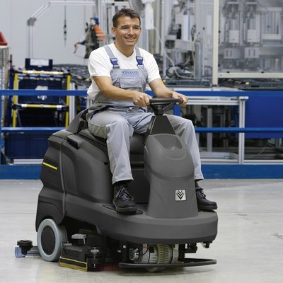 A Karcher (65/90) Ride-on Floor Scrubber Dryer being operated in a workshop.