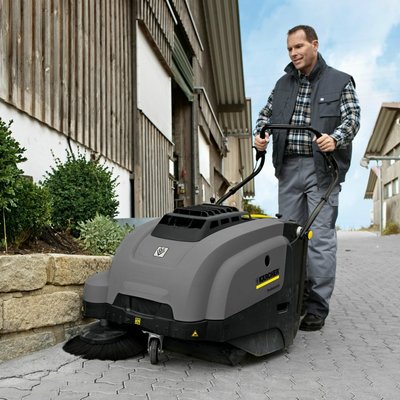 A man operating a Karcher (KM 75/40 W) Floor Sweeper outdoors.