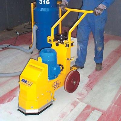 A diamond floor grinder being operated by a man in a blue suit.