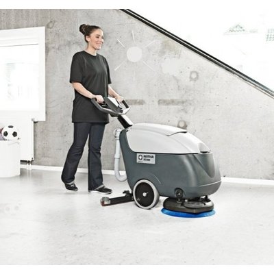 A Nilfisk SC400 Floor Scrubber Dryer being operated by a woman in a home.