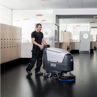 A Nilfisk SC530 Floor Scrubber Dryer being operated by a person inside a workplace.