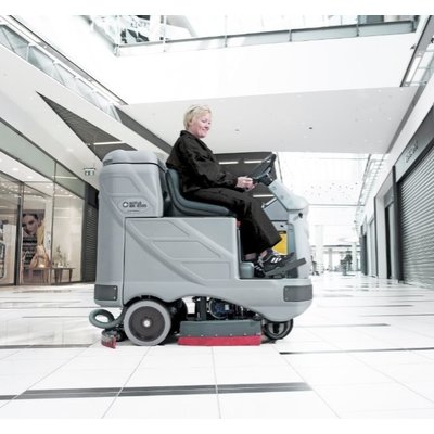 A Nilfisk BR850S Ride-on Floor Scrubber Dryer being used in a shopping centre.