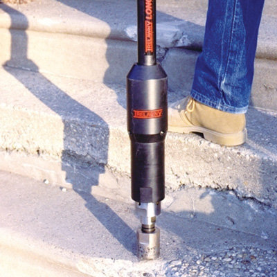 A Pole Scabbler - Low Vibration being operated by a person on a floor outside.