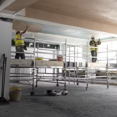 Two men using the boxing ring tower to complete some work in a warehouse.